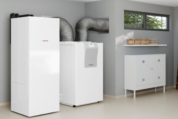 Zwei moderne Wärmepumpen von ieQ Defaultsite in einem Technikraum in Münster, mit Lüftungsrohren und Fenster.